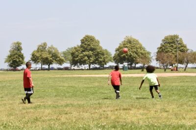 3 youth play soccer in greenish field