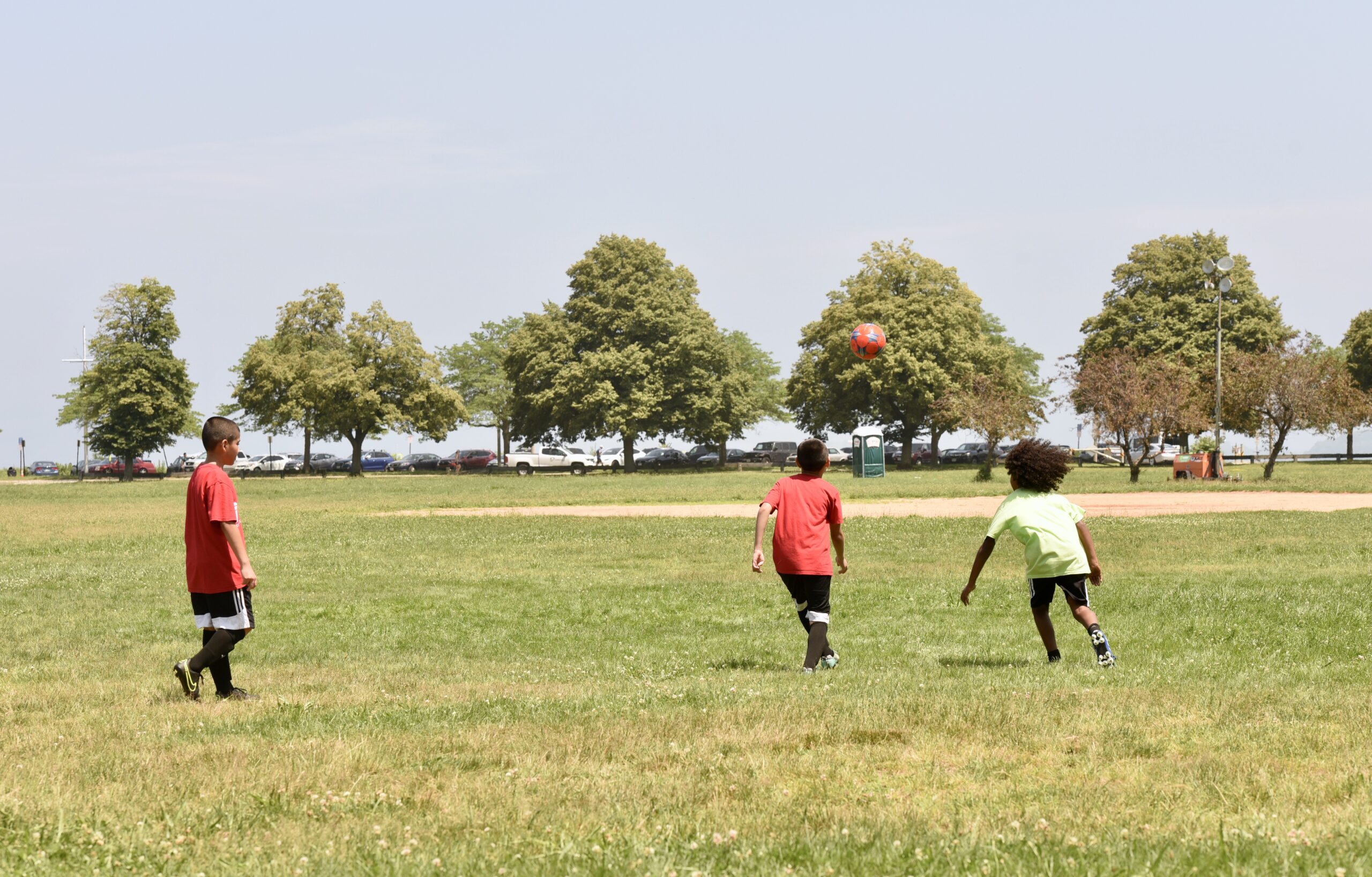 3 youth play soccer in greenish field