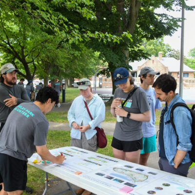 People stand around a table with plans for Moakley park renovations.